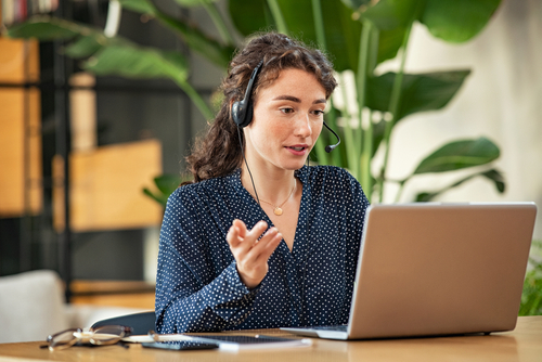 employée assurant un support interne à distance via visioconférence sur ordinateur portabl